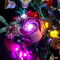 Pink rose from LEGO Pretty Pink Flower Bouquet #10342 glowing with white LED light, surrounded by other lit floral pieces.